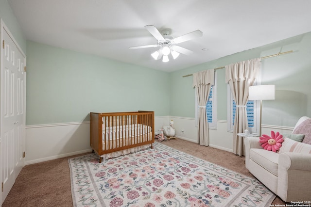 bedroom with ceiling fan, a closet, a nursery area, and carpet flooring