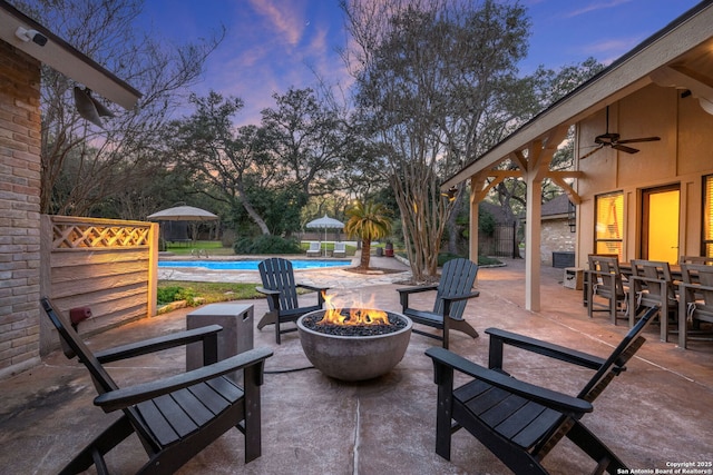 patio terrace at dusk featuring a fire pit and ceiling fan