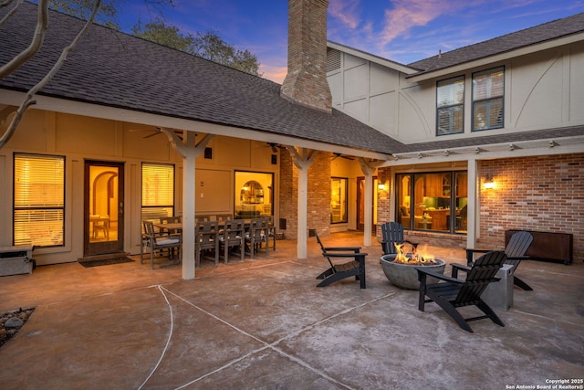 patio terrace at dusk with ceiling fan and a fire pit