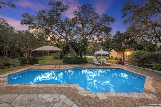 pool at dusk featuring a patio area and a gazebo