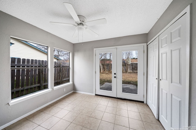 unfurnished sunroom featuring ceiling fan and french doors