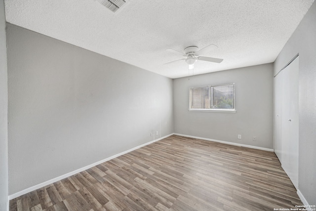 spare room featuring ceiling fan, wood-type flooring, and a textured ceiling