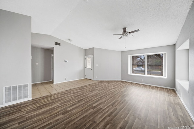 unfurnished living room featuring ceiling fan, vaulted ceiling, a wealth of natural light, and hardwood / wood-style floors