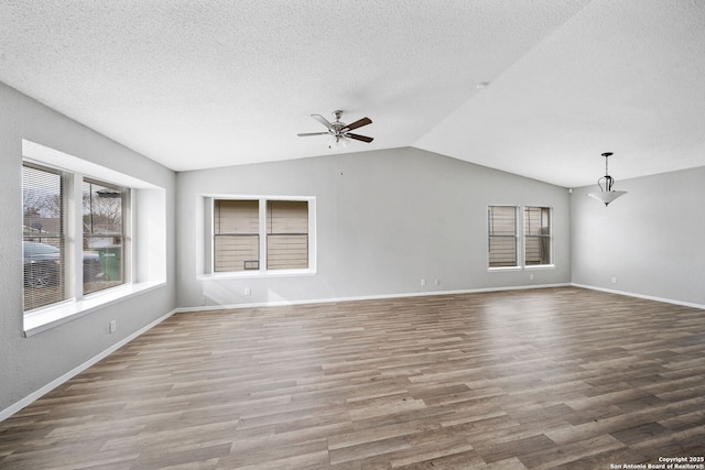 unfurnished living room with hardwood / wood-style flooring, lofted ceiling, a textured ceiling, and ceiling fan