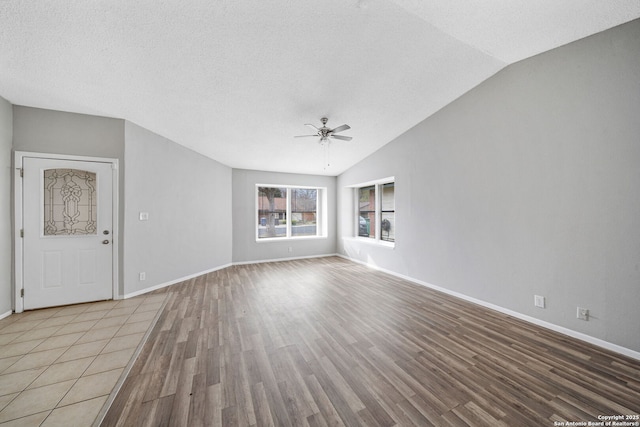 unfurnished living room featuring light wood-type flooring, vaulted ceiling, ceiling fan, and a textured ceiling