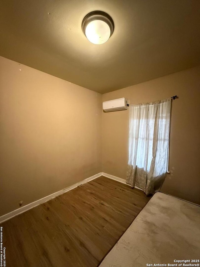 unfurnished bedroom featuring dark wood-type flooring and a wall mounted air conditioner