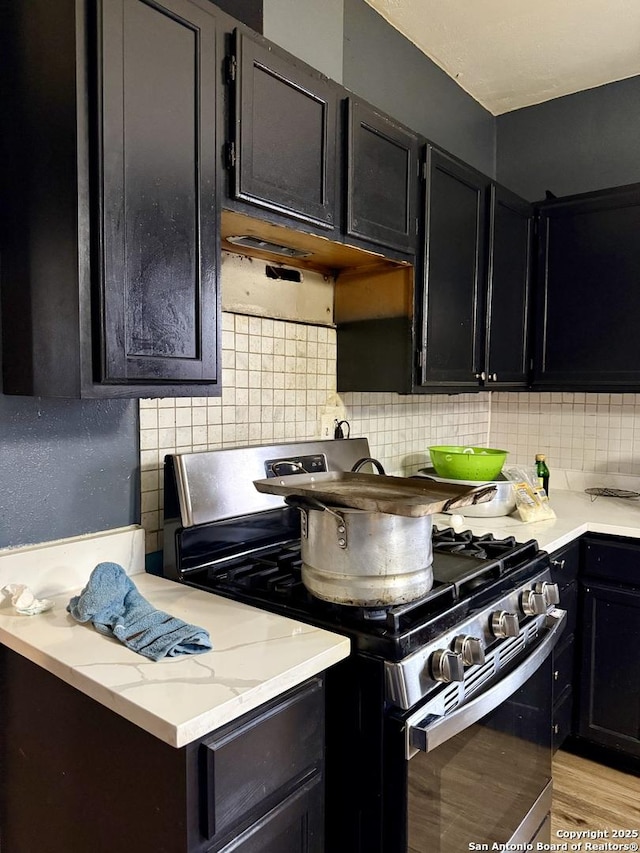 kitchen with light hardwood / wood-style flooring, tasteful backsplash, and gas stove