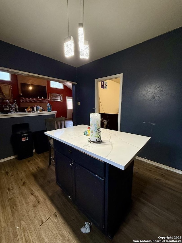 kitchen with dark wood-type flooring, a kitchen island, and decorative light fixtures