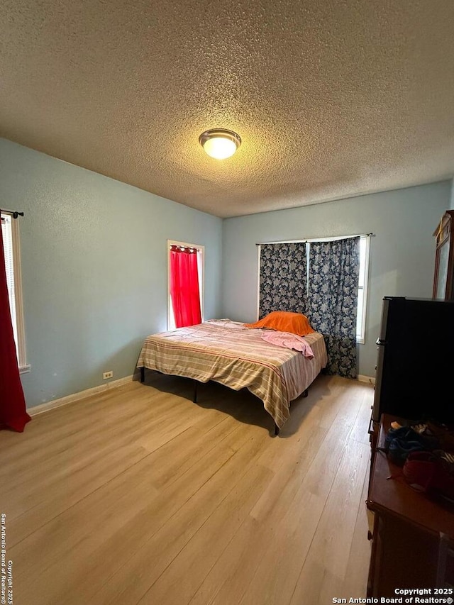 bedroom with light wood-type flooring and a textured ceiling