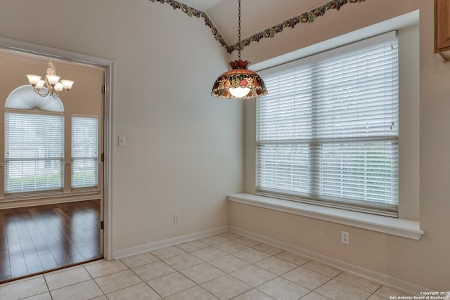 unfurnished dining area with light tile patterned floors, a chandelier, and vaulted ceiling