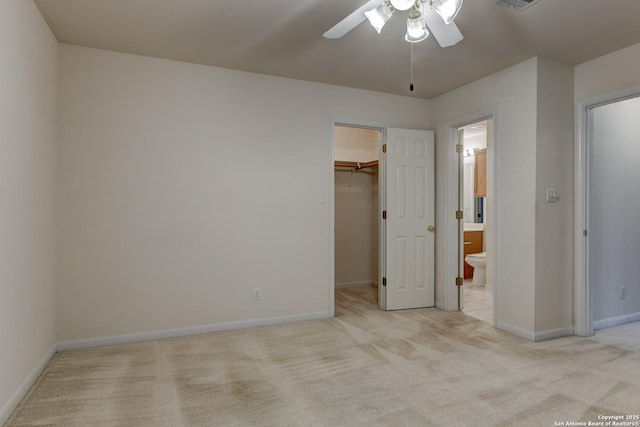 unfurnished bedroom with ceiling fan, light carpet, a walk in closet, and ensuite bath