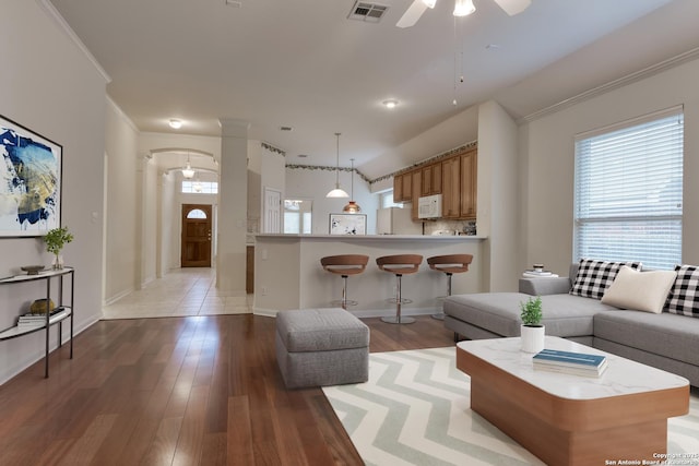 living room with light hardwood / wood-style floors, ceiling fan, and ornamental molding