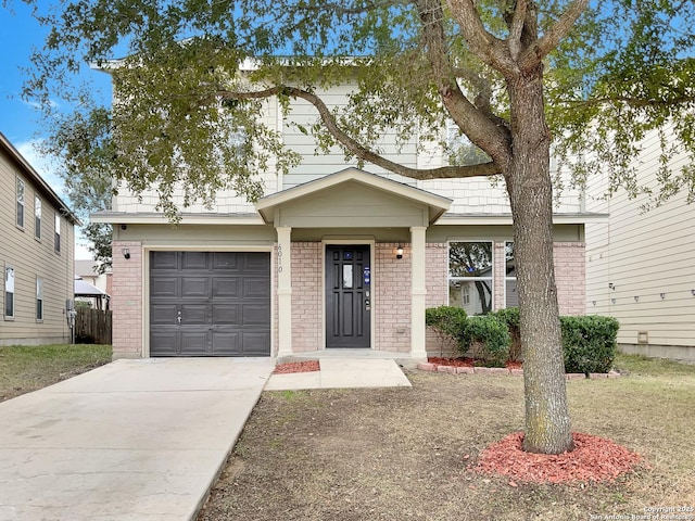 traditional-style house featuring a garage, concrete driveway, and brick siding