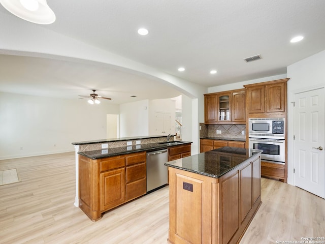 kitchen with light wood-type flooring, a kitchen island, tasteful backsplash, and stainless steel appliances