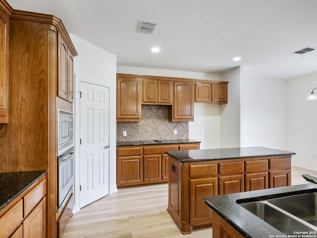 kitchen with a center island, sink, backsplash, oven, and stainless steel microwave