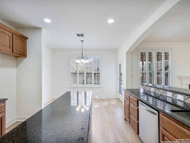 kitchen featuring dark stone countertops, a notable chandelier, pendant lighting, and dishwasher