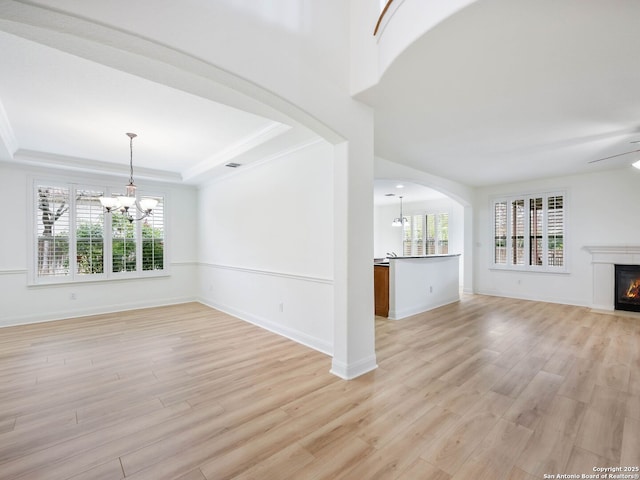 unfurnished living room with a healthy amount of sunlight, light hardwood / wood-style flooring, a tray ceiling, and ornamental molding