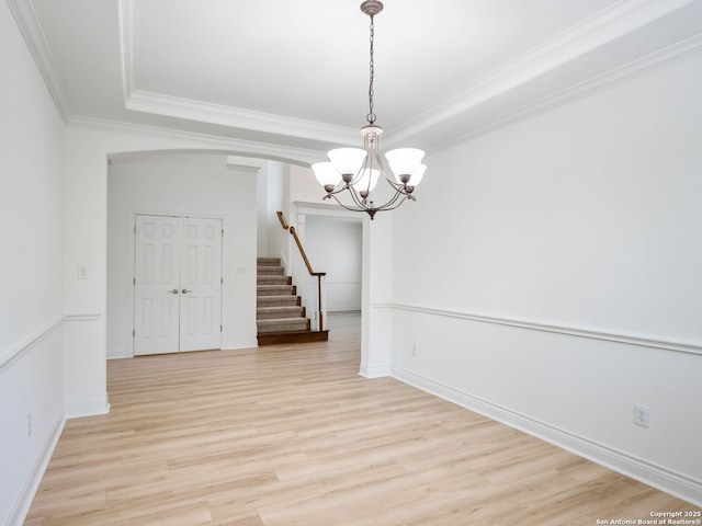 unfurnished room with light hardwood / wood-style flooring, crown molding, a chandelier, and a raised ceiling