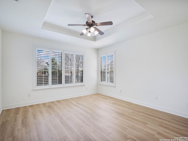 unfurnished room with a tray ceiling, light hardwood / wood-style floors, and a healthy amount of sunlight