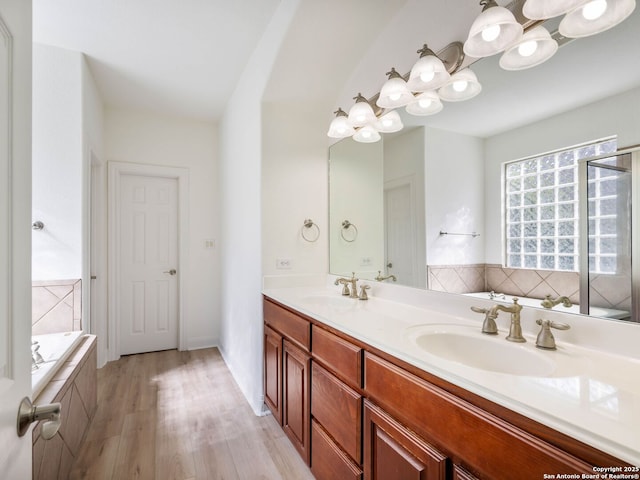 bathroom with vanity, hardwood / wood-style floors, and a relaxing tiled tub