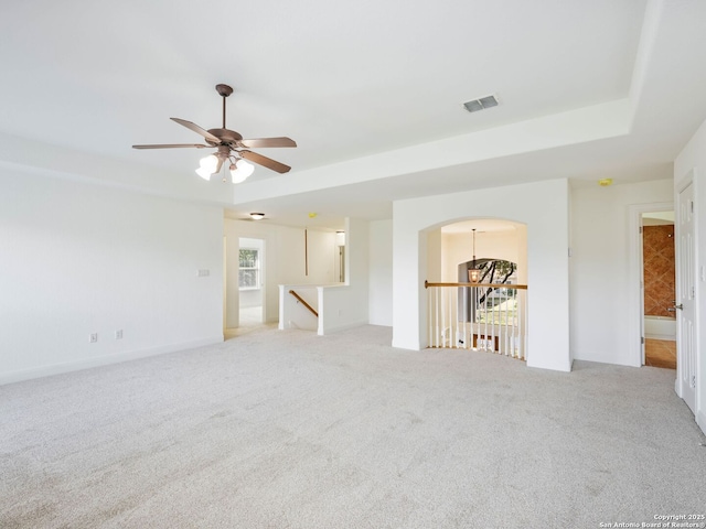 unfurnished room featuring light carpet, ceiling fan, and a tray ceiling