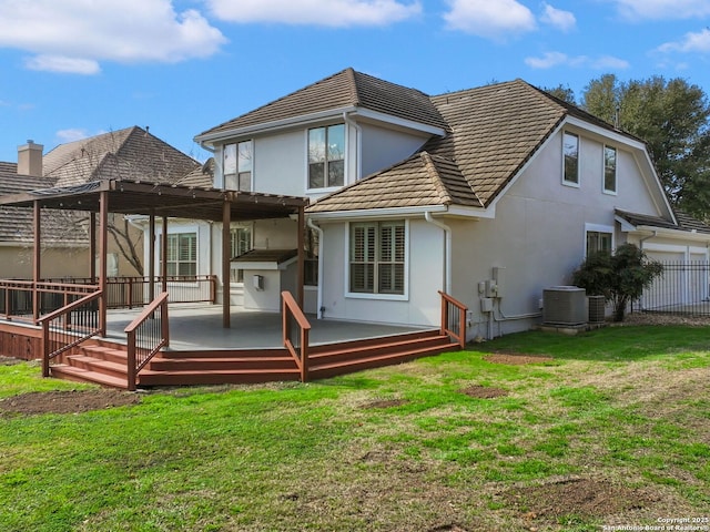 rear view of house with central AC, a wooden deck, and a lawn