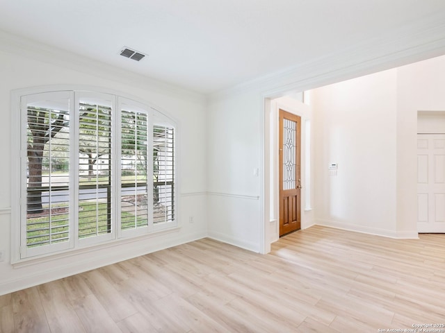 empty room with light hardwood / wood-style floors and crown molding