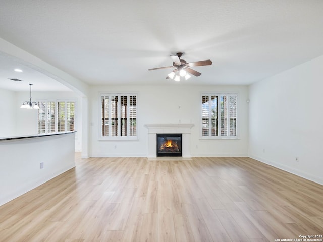 unfurnished living room featuring light wood-type flooring and ceiling fan with notable chandelier