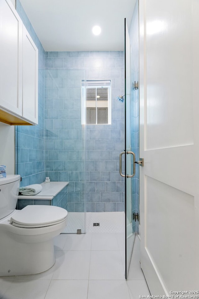 bathroom with toilet, tile patterned flooring, and a shower with shower door