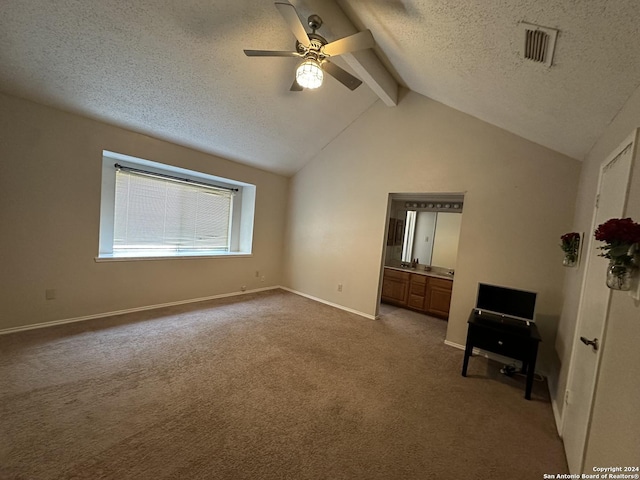 unfurnished bedroom with lofted ceiling with beams, a textured ceiling, ensuite bathroom, ceiling fan, and light carpet