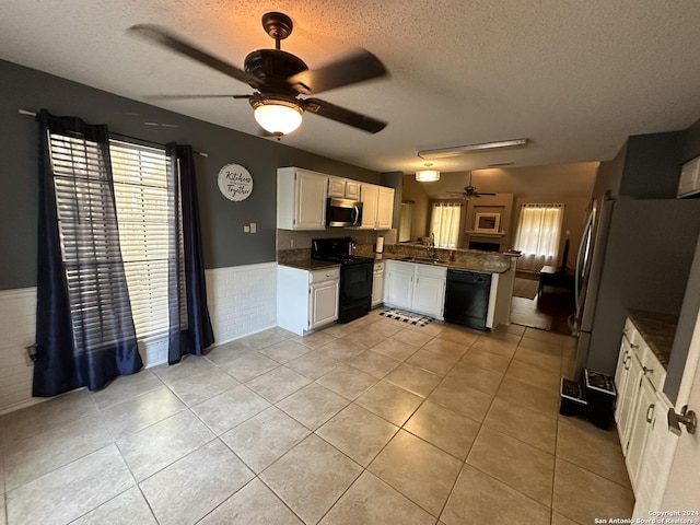 kitchen featuring white cabinets, light tile patterned floors, black appliances, and a textured ceiling