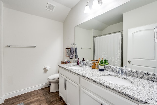 bathroom with toilet, hardwood / wood-style flooring, vaulted ceiling, and vanity