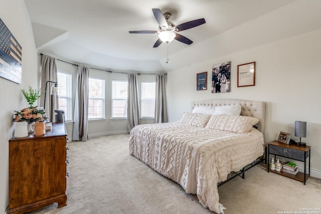 carpeted bedroom featuring ceiling fan and a tray ceiling