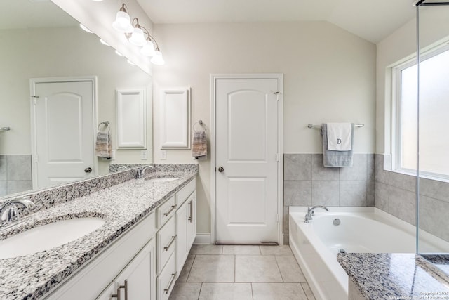 bathroom featuring a bathing tub, vanity, tile patterned floors, and lofted ceiling