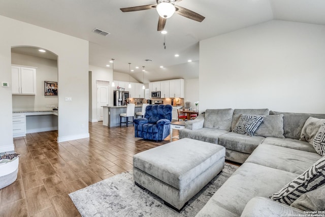 living room with hardwood / wood-style floors, vaulted ceiling, and ceiling fan