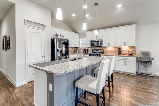 kitchen with white cabinetry, appliances with stainless steel finishes, sink, and an island with sink