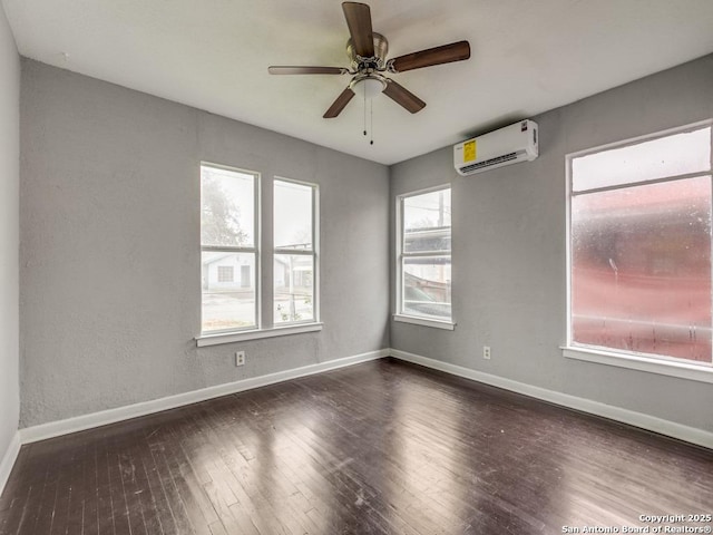 spare room with an AC wall unit, ceiling fan, and dark wood-type flooring