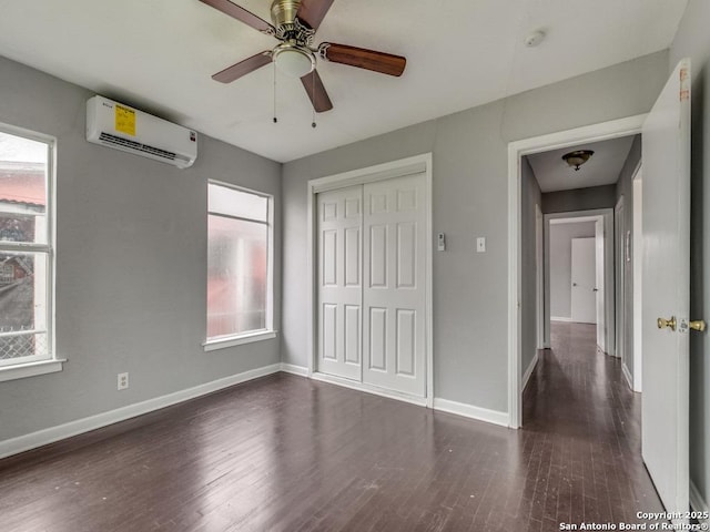 unfurnished bedroom featuring ceiling fan, a wall mounted AC, dark hardwood / wood-style floors, and a closet