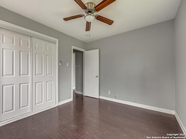 unfurnished bedroom featuring ceiling fan, a closet, and dark wood-type flooring