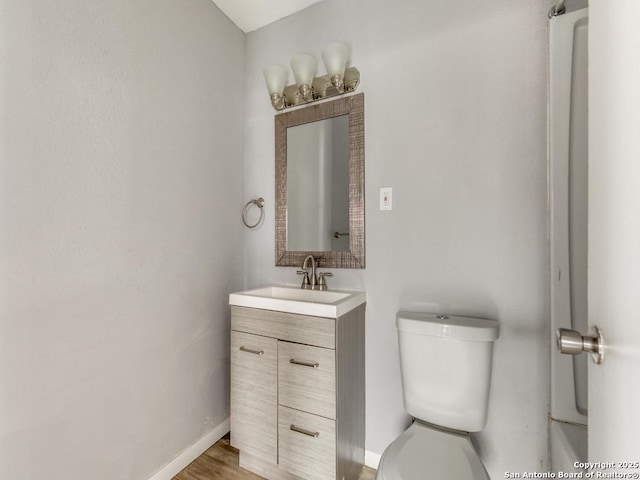 bathroom with vanity, toilet, and hardwood / wood-style floors