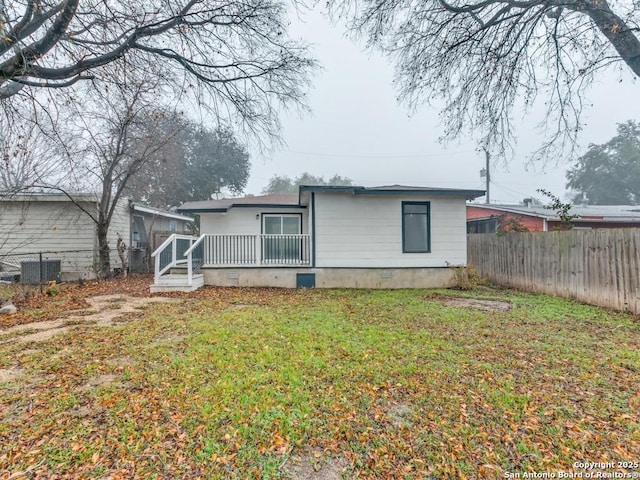 rear view of property featuring a yard, a deck, and central AC