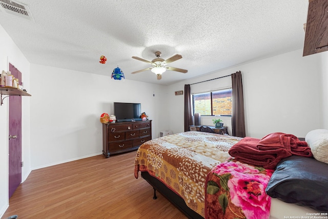 bedroom with ceiling fan, light wood-type flooring, and a textured ceiling