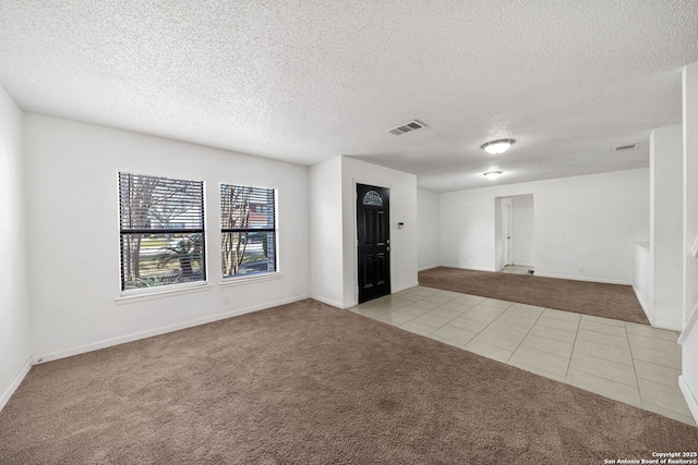 spare room with light carpet and a textured ceiling