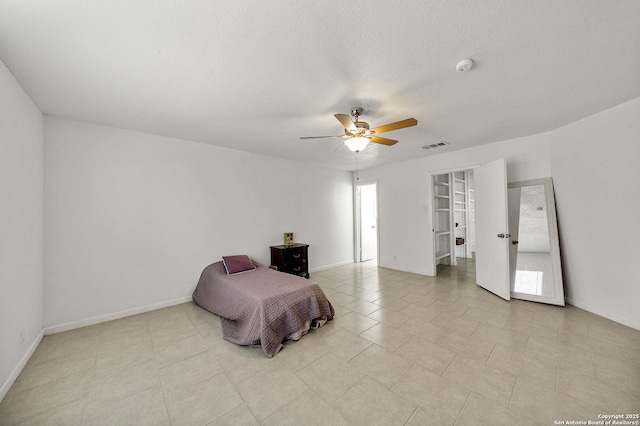 bedroom with ceiling fan, light tile patterned flooring, and a textured ceiling