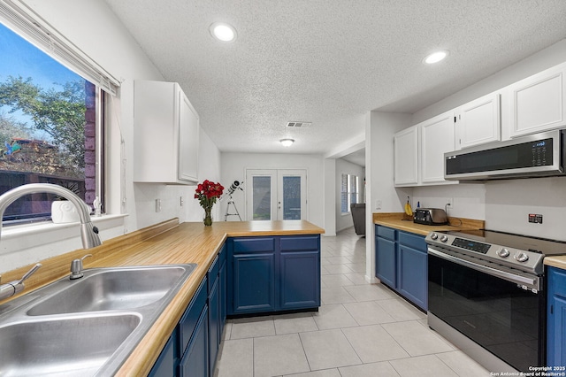 kitchen with sink, white cabinetry, blue cabinetry, stainless steel appliances, and french doors