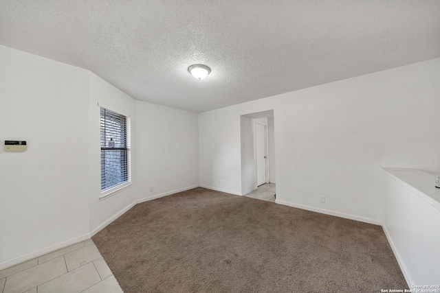 empty room with a textured ceiling and light colored carpet