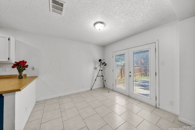 tiled spare room with french doors and a textured ceiling