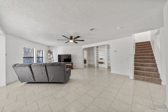 living room with ceiling fan, light tile patterned flooring, and a textured ceiling