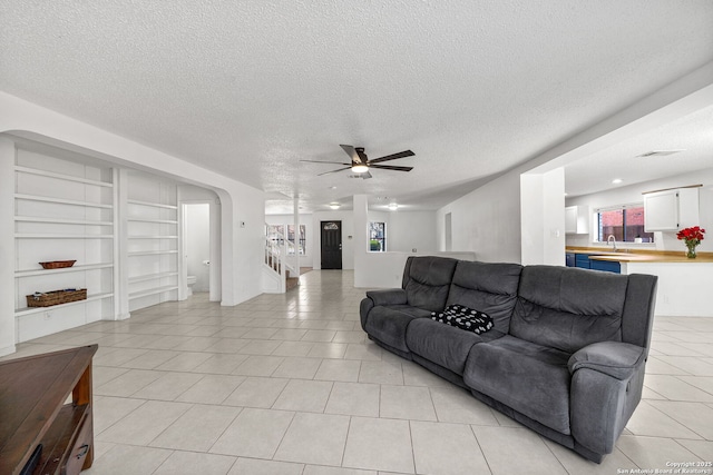 living room with sink, a textured ceiling, ceiling fan, and light tile patterned floors