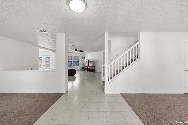 entryway featuring ceiling fan, a textured ceiling, and light colored carpet